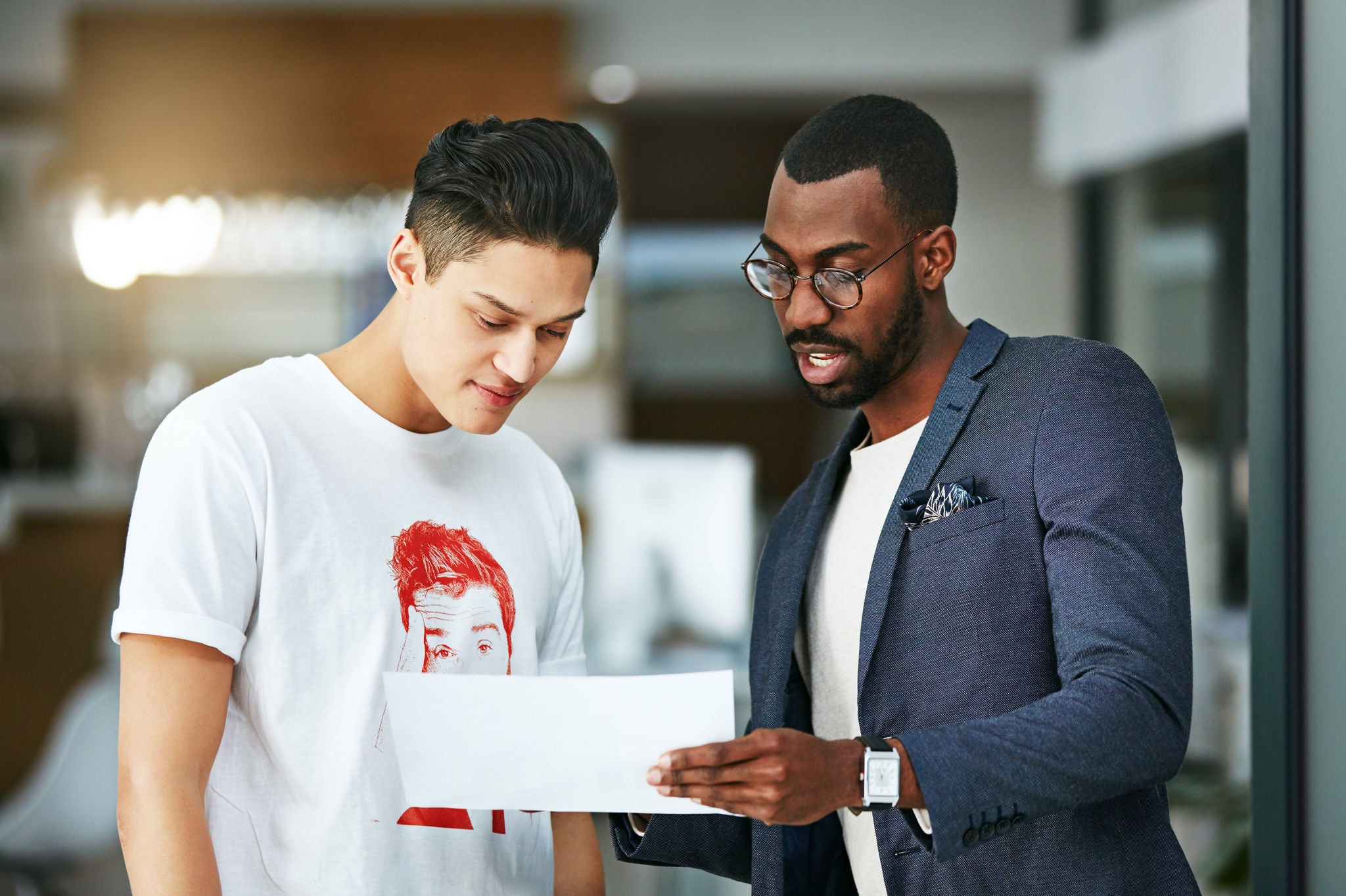 Mentor erklärt jungem Trainee ein Projekt auf einem Blatt