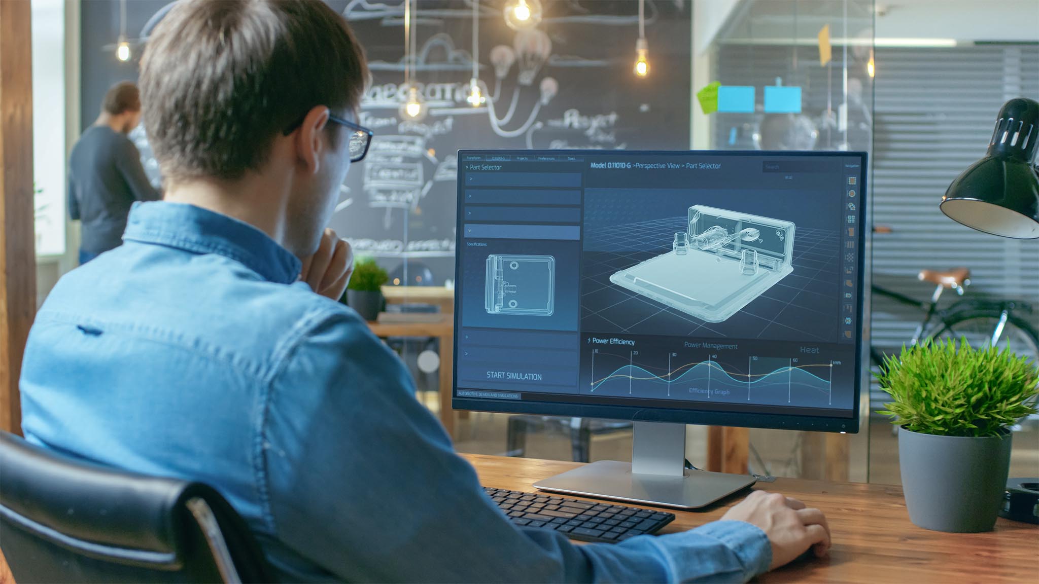 Financier Works on a Personal Computer Showing Statistics, Graphs and Charts. In the Background His Coworker and Creative Office.