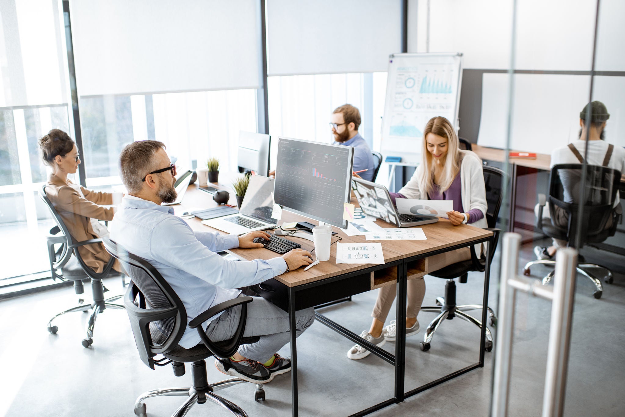 Group of diverse colleagues working on the computers in the modern office or coworking space, writing programming code