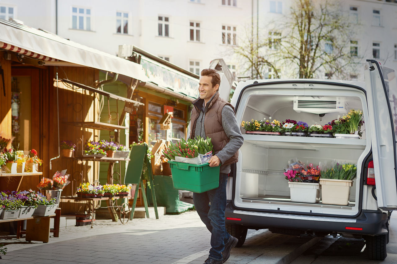 Man on market in front of van with flowers